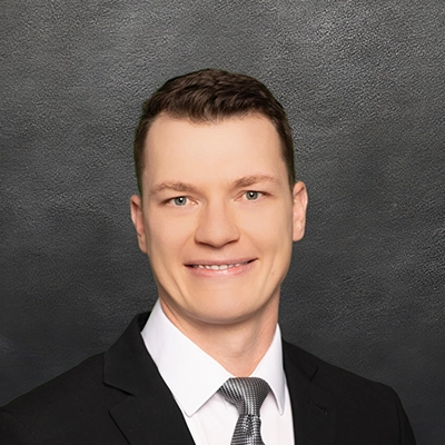 Chiropractor Brandon Wedig Smiling In Front Of Black Wall